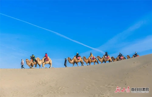 游客骑骆驼畅游敦煌鸣沙山，领略大漠好风光